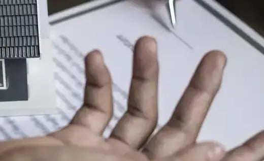 Close-up of a hand signing a document, representing a major financial asset acquisition. This asset must be registered.