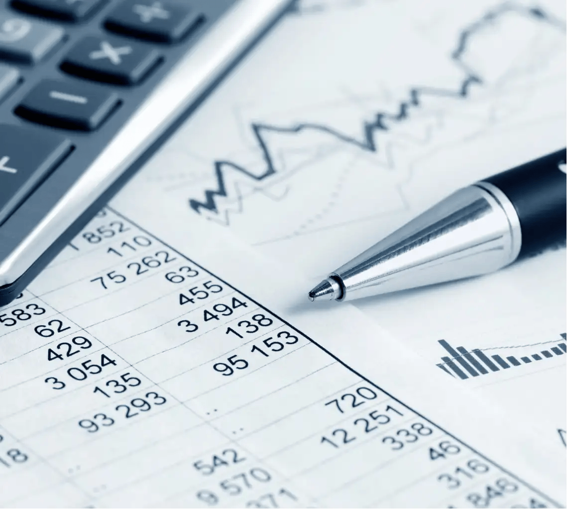 A close-up of a printed financial report with calculator and pen on the top of these, a contrast to the efficiency of cloud accounting in which there is no need to keep manual records.