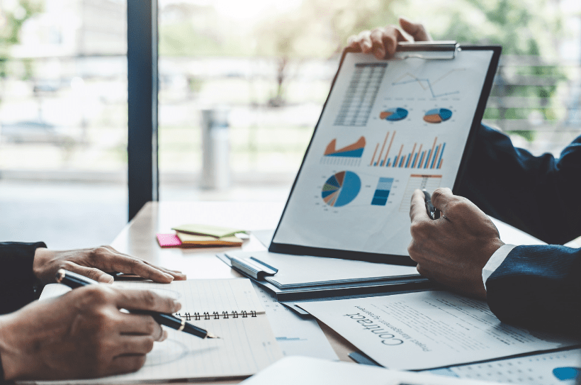 A business meeting between two business owners with one showing their finance statistics to demonstrate how they can achieve their company growth project.